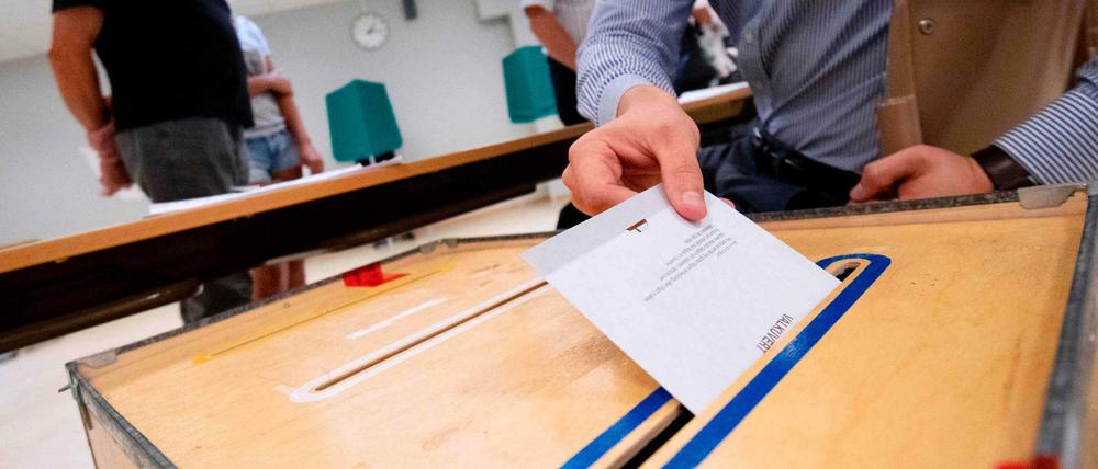 Ein Wähler schmeißt seinen Wahlzettel in die Urne.