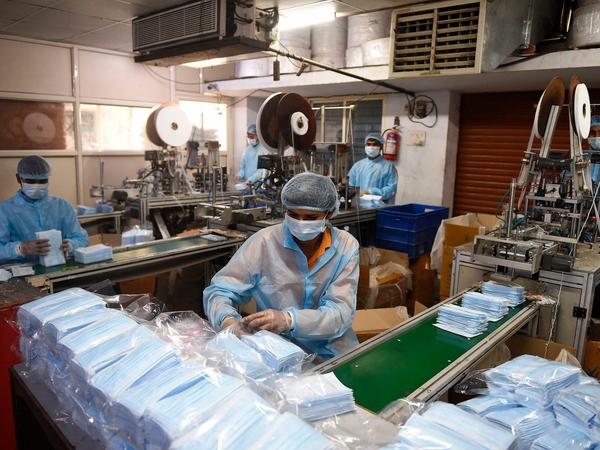 Mitarbeiter packen in einer Produktionsstätte Schutzmasken ein. Die Nachfrage ist stark gestiegen.