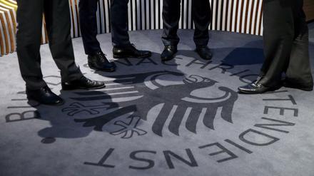 Männer stehen auf einem Teppich mit dem Logo des Geheimdienstes während der Eröffnung des Besucherzentrums des Bundesnachrichtendienstes (BND).