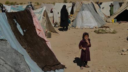 A girl stands next to tents at a temporary camp near a highway between Herat and Badghis on October 14, 2021. (Photo by Hoshang Hashimi / AFP)