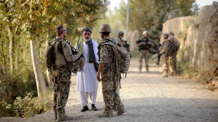 Ein Bundeswehrsoldat (li.) und sein afghanischer Dolmetscher (re.), der als Ortskraft angestellt war, sprechen mit einem Mann bei Kudus (Archivbild): 