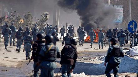Afghanische Polizisten laufen nahe einer US-Militärbasis in Kabul den Demonstranten entgegen. Autos wurden abgezündet, mehrere Menschen wurden verletzt.
