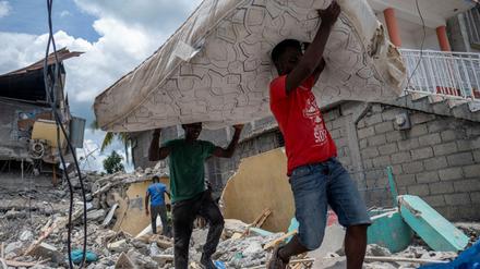 Erdbeben auf Haiti: Männer tragen eine Matratze aus einem zerstörten Hotel.