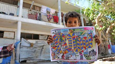 Der elfjährige Ahmed mit einem Spiel, das Flüchtlingskinder vor den Gefahren von Landminen warnen soll.