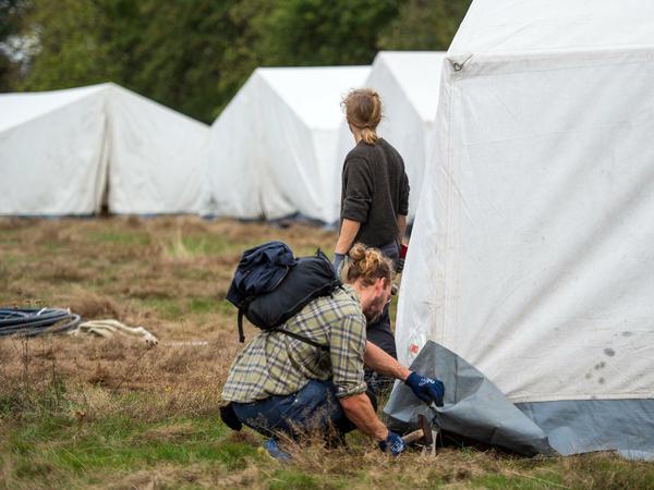 Zwei Aktivisten bauen ein Zelt auf dem ehemaligen Sportplatz in Manheim-alt auf.