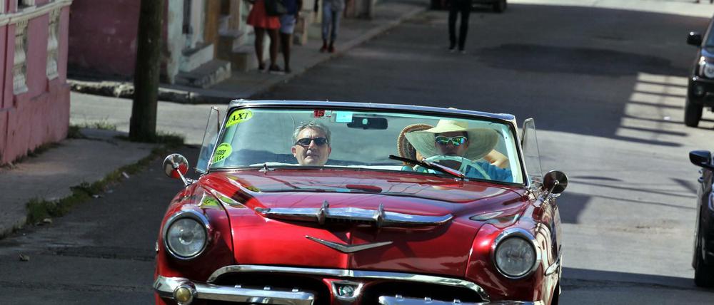 Touristen fahren in einem Oldtimer durch die kubanische Hauptstadt Havanna.