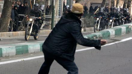 An Iranian protester throws a stone at riot police during fierce clashes in central Tehran