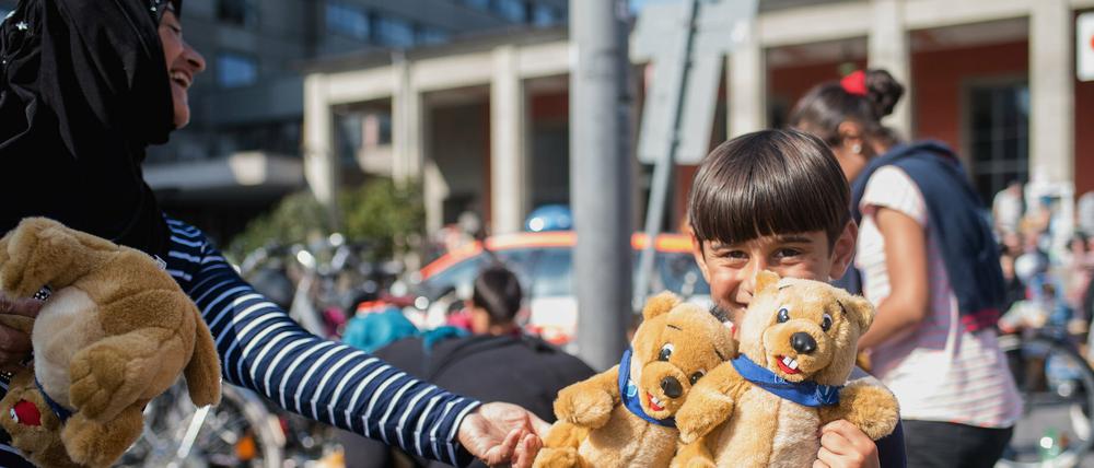 Ein Flüchtlingskind freut sich am am Hauptbahnhof von München über geschenkte Stofftiere.