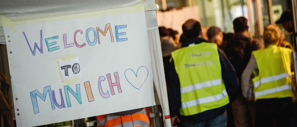 Freiwillige Helfer stehen am 05.09.2015 am Hauptbahnhof in München neben dem Schild "Welcome to Munich". 