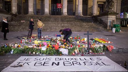 Ein Passant zündet am 23.03.2016 in Brüssel vor der Börse am Place de la Bourse hinter einem Banner mit der Aufschrift "Je suis Bruxelles Ik ben Brussel" eine Kerze an.