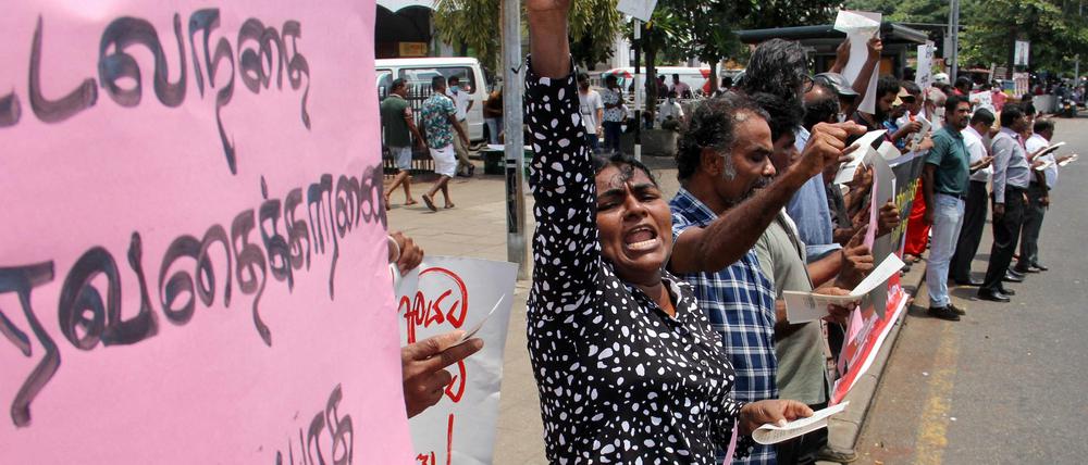 Protestierende stehen mit Plakaten an einer Straße in Colombo.