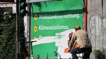 Ein beschädigtes Plakat mit den Schriftzügen "Wohlstandsvernichtung" und "Klimasozialismus" hängt am Straßenrand.