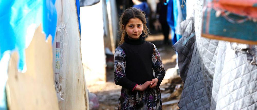 Ein syrisches Mädchen steht zwischen provisorischen Zelten, die auf dem Weg in die Türkei errichtet wurden. 