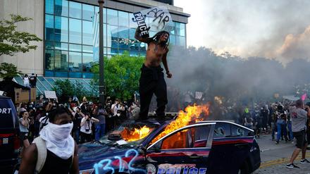 Ein Demonstrant steht auf einem brennenden Polizeiauto in Atlanta. =