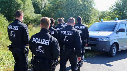 Polizisten durchsuchen am Morgen nach dem Axt-Angriff eines Afghanen das Gelände neben einem Weg bei Würzburg nach Spuren. 