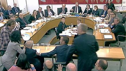 Angriff von links. Rupert Murdoch wird von einem Mann (links im Bild) während der Anhörung im Parlament attackiert.