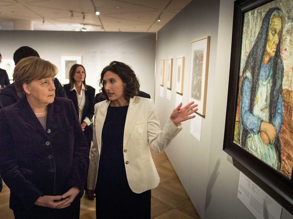 Die Kuratorin Eliad Moreh-Rosenberg erläutert Bundeskanzlerin Angela Merkel (CDU) in Gemälde in der Ausstellung "Kunst aus dem Holocaust" in Berlin.