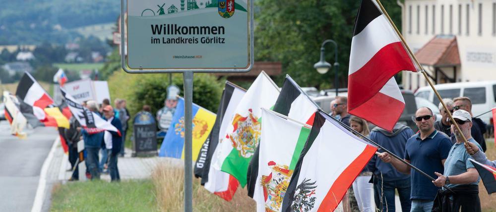 Rechte Teilnehmer eines Corona-Protests stehen mit Fahnen, darunter die Flagge des deutschen Kaiserreiches, an der Bundesstraße 96.