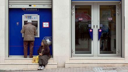 Eine Frau bettelt vor einer Bankfiliale in Athen.