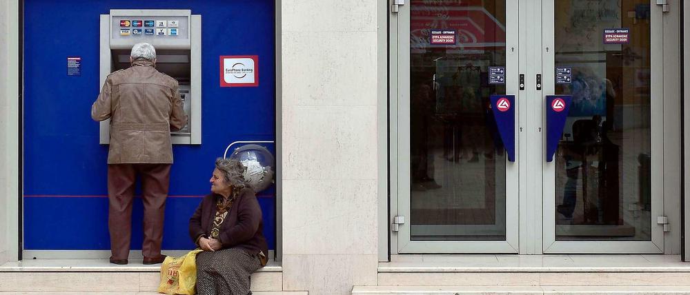 Eine Frau bettelt vor einer Bankfiliale in Athen.
