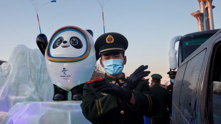 Ein Polizist in Peking vor einem Maskottchen der Olympischen Winterspiele 