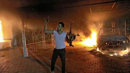 Ein Mann steht mit seiner Waffe vor dem brennenden US-Konsulat in Bengasi.