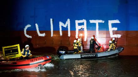 Greenpeace-Aktivisten bemalen auf der Weser das Frachtschiff "Hiroshima Star" mit dem Schriftzug "Climate Crime" (Klimaverbrechen).