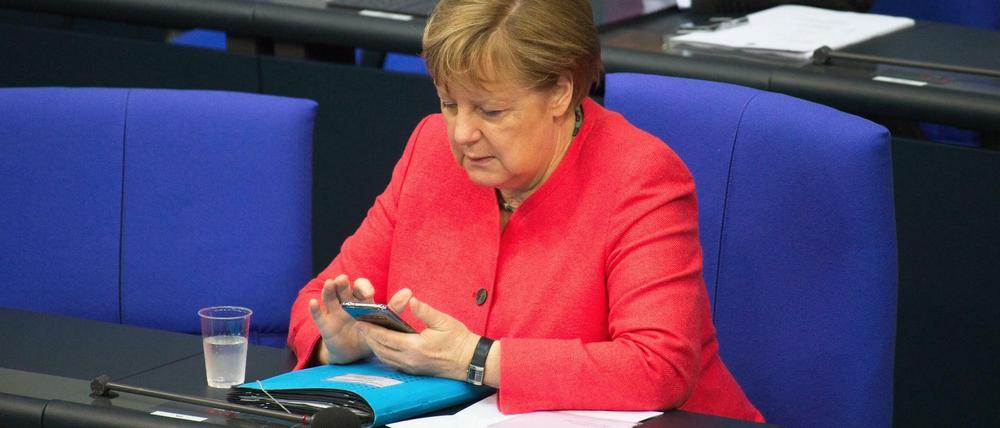 Das Mobiltelefon im Blick: Bundeskanzlerin Angela Merkel im Bundestag (Archivbild)