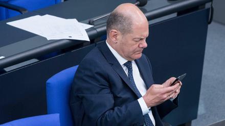 Olaf Scholz mit Blick auf sein Handy im Bundestag (Archivbild) 