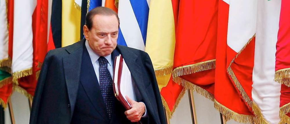 Den Mantel hat er schon um, die Akten in der Hand. Sieht alles nach einem Aufbruch aus bei Italiens Premier Berlusconi. 
