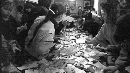 Erfurter Bürger drängen sich am 4. Dezember 1989 in der Stasi-Bezirksverwaltung um einen Tisch mit zerrissenen Unterlagen. 