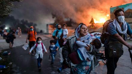 Migranten fliehen vor einem erneuten Feuers mit ihren Habseligkeiten aus dem Flüchtlingslager Moria