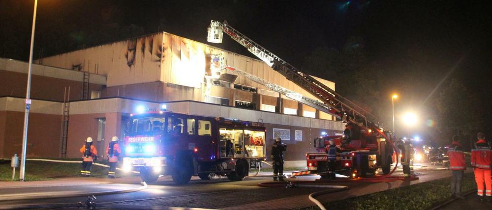 Einsatzkräfte der Feuerwehr löschen den Brand in der Unterkunft in Wertheim in Baden-Württemberg. In der Sporthalle standen seit Samstag 330 Betten.