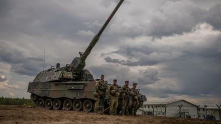 Soldaten stehen vor einem gepanzerten, selbstfahrenden Artilleriegeschütz vom Typ Panzerhaubitze 2000 der Bundeswehr.