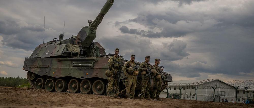 Soldaten stehen vor einem gepanzerten, selbstfahrenden Artilleriegeschütz vom Typ Panzerhaubitze 2000 der Bundeswehr.