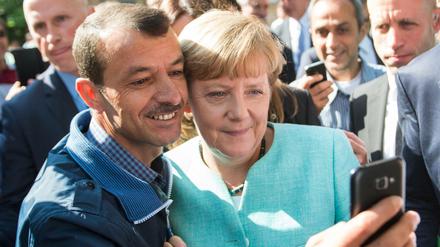 Ein Symbolbild der Willkommenskultur: Bundeskanzlerin Angela Merkel posiert beim Besuch einer Erstaufnahmeeinrichtung Berlin-Spandau für ein Selfie mit einem Flüchtling.