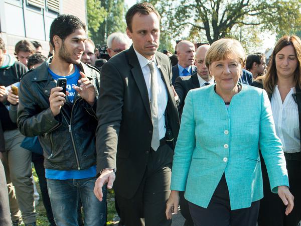 Bundeskanzlerin Angela Merkel (M, CDU) geht am 10.09.2015 in die Außenstelle des Bundesamtes für Migration und Flüchtlinge in Berlin-Spandau, nachdem sie dort wartende Asylbewerber begrüßt hat. 