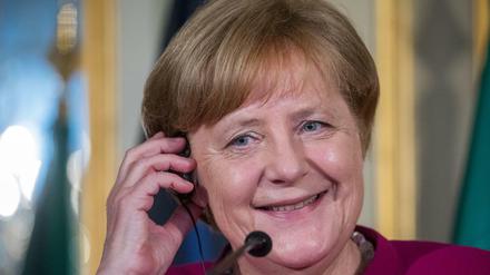 Bundeskanzlerin Angela Merkel hält sich bei einer Pressekonferenz bei ihrem Besuch in Portugal im Palácio Foz einen Kopfhörer ans Ohr.