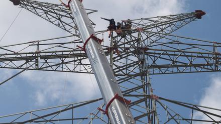 Arbeiter bauen Masten für Hochspannungsleitungen auf einer Tennet-Baustelle.