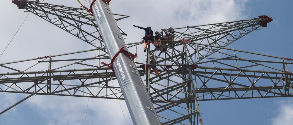 Arbeiter bauen Masten für Hochspannungsleitungen auf einer Tennet-Baustelle.