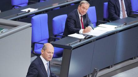 Olaf Scholz (SPD) spricht im Plenum im Deutschen Bundestag. Armin Laschet (CDU) lauscht und notiert.
