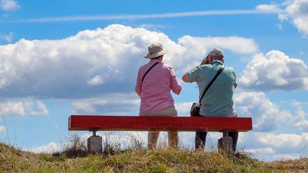 Zwei ältere Personen sitzen auf einer Bank, die auf einem Hügel im Nationalpark Unteres Odertal steht. 