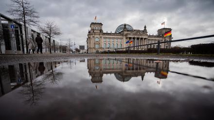 Das Reichstagsgebäude spiegelt sich am Morgen in einer Pfütze.