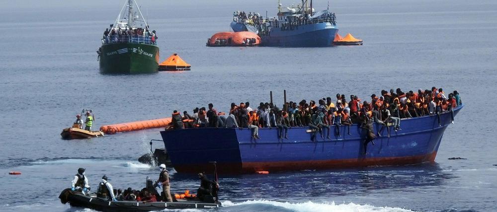 Marinesoldaten fahren mit einem Boot zu einem überfüllten Flüchtlingsboot auf dem Mittelmeer. 