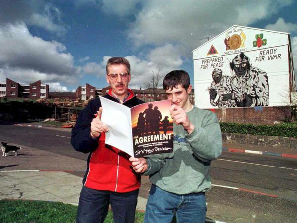 Vor 20 Jahren: Zwei Männer lesen das Karfreitagsabkommen, im Hintergrund Graffities der IRA.
