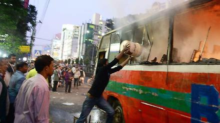 Gewalt in Bangladesch. Freiwillige löschen einen Bus, der vermutlich von Regierungsgegnern in Brand gesteckt worden war.