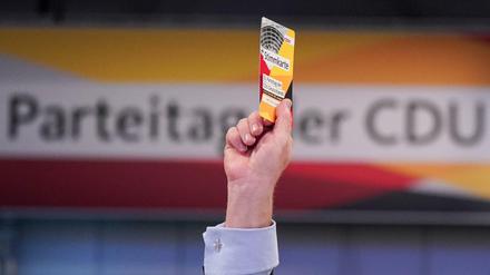 Ein Delegierter hält beim 32. CDU-Bundesparteitag seine Stimmkarte hoch.