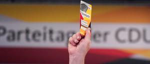 Ein Delegierter hält beim 32. CDU-Bundesparteitag seine Stimmkarte hoch.