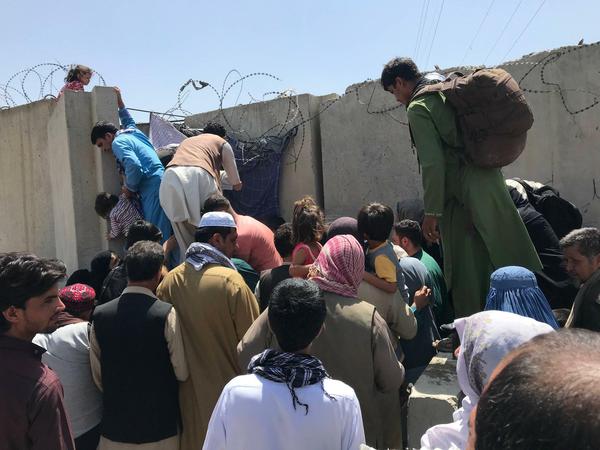 Menschen versuchen, die Mauern rund um den Flughafen in Kabul zu überwinden.