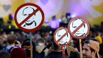 Bei einer Demo in Wien tragen Teilnehmende Schilder mit dem durchgestrichenen Konterfei des russischen Präsidenten Putin.